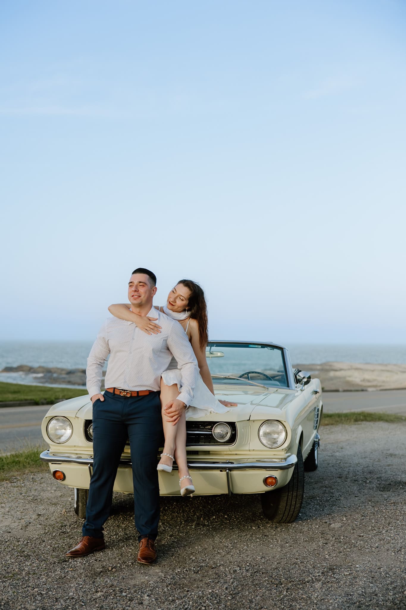Couple posing with antique car for engagement photos on Ocean Drive in Newport, RI