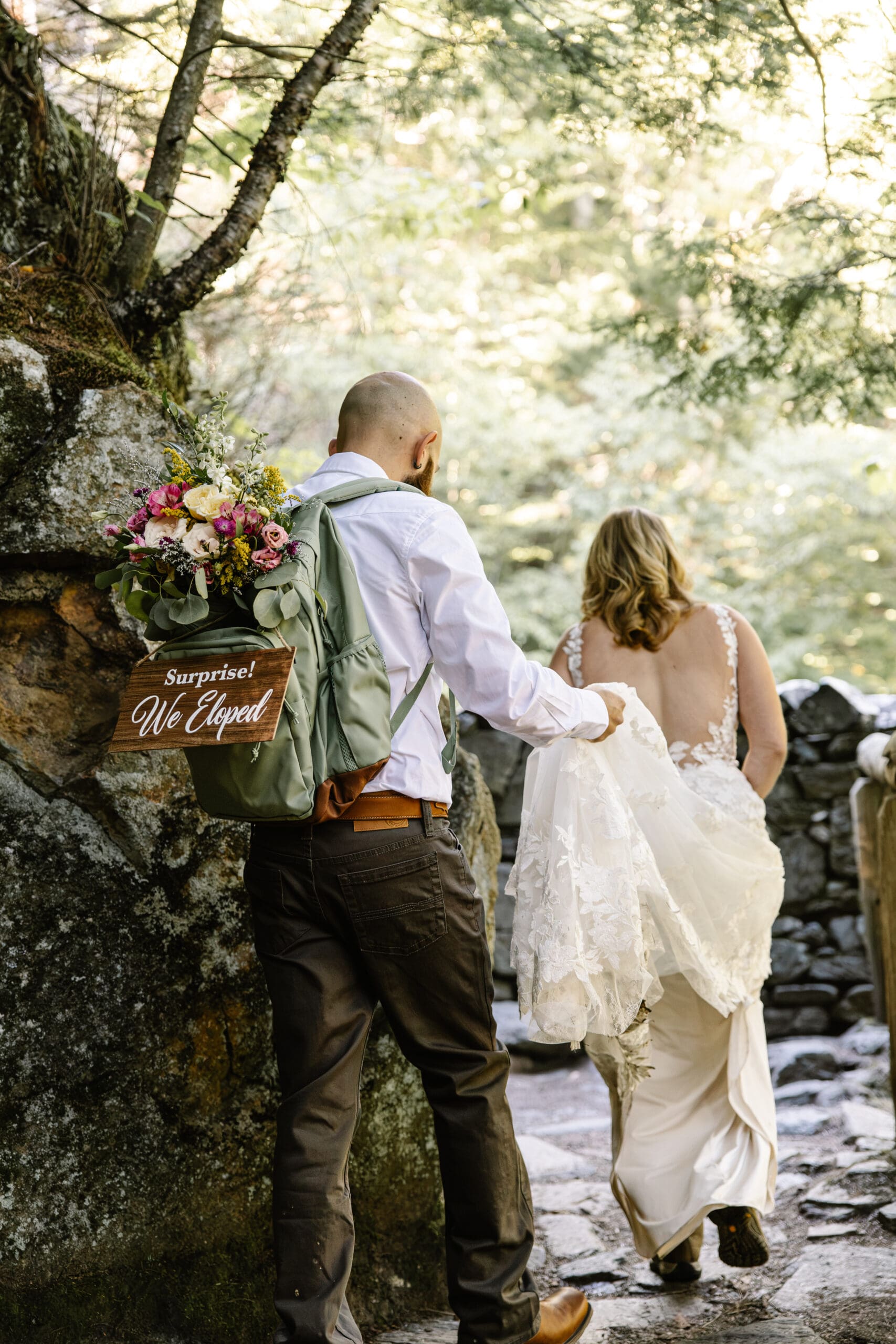 Newlyweds walking along the trail at Glen Ellis Falls after their intimate White Mountains elopement ceremony.